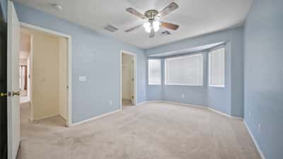 Spacious primary bedroom enjoys a large bay window, ceiling fan, plush carpeting, and direct access to the ensuite bath. A peaceful retreat with plenty of room to personalize.