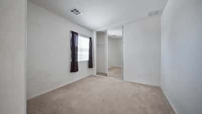 Bright secondary bedroom features plush carpeting, mirrored closet doors, and plenty of natural light. Ideal for guests, family, or a dedicated home office in this Buckeye property.