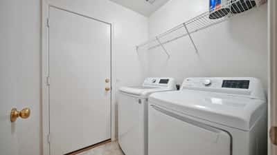 Well-designed laundry room includes washer and dryer, built-in shelving, and convenient access to the backyard. A practical feature that enhances everyday living.