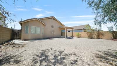 Rear exterior showcases the covered patio and spacious backyard with plenty of room to relax, entertain, or personalize with future landscaping and outdoor amenities.