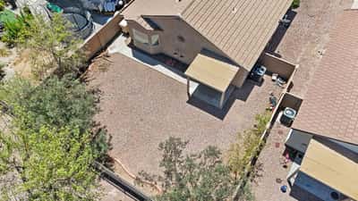 Bird's-eye view captures the backyard layout, covered patio, mature landscaping, and spacious outdoor area, providing an excellent perspective of the property's generous rear yard.