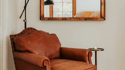 Cozy leather armchair and a vintage mirror create a warm, inviting corner in this living space.