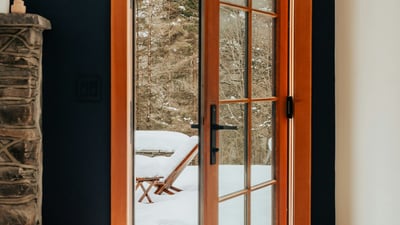 Bright entryway featuring a wooden door opening to a snowy outdoor retreat, perfect for winter getaways.