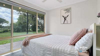 Bright and airy bedroom with large windows offering stunning views of the lush backyard.