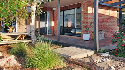 Contemporary home featuring expansive windows and an inviting outdoor space surrounded by lush greenery.