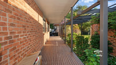 Inviting walkway lined with brick and greenery, leading to a secluded outdoor living space.