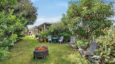 Nestled in lush greenery, this inviting outdoor space features seating areas and a fire pit for gatherings.