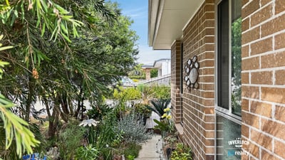 Welcome home to this inviting entrance surrounded by lush landscaping and vibrant greenery.