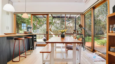 Bright and inviting kitchen and dining area seamlessly connect to a lush outdoor space, perfect for gatherings.