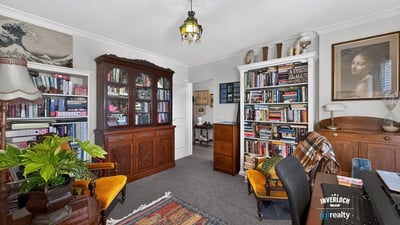 Cozy home office with built-in bookshelves, vintage furnishings, and ample natural light for productivity.