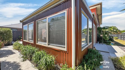 This contemporary home features expansive windows, inviting natural light and showcasing the surrounding greenery.