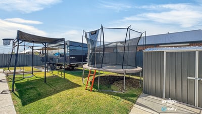 Spacious backyard featuring a trampoline, perfect for outdoor fun and family gatherings, with ample storage options.