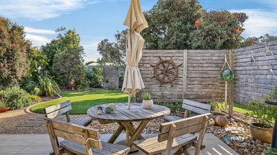 Enjoy outdoor living in this inviting patio, featuring a cozy seating area and lush greenery.