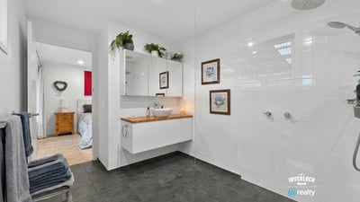 Modern bathroom featuring spacious walk-in shower, dual rainfall showerheads, and sleek cabinetry for organized storage.