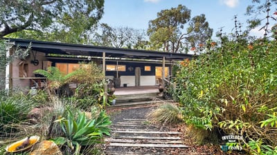 This inviting home features a spacious front porch and lush gardens, perfect for outdoor relaxation.