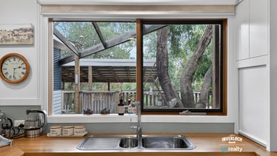 Bright kitchen featuring a large window that overlooks a spacious backyard with mature trees.