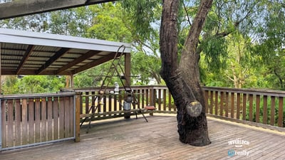 Spacious deck surrounded by lush greenery, perfect for outdoor gatherings and relaxation in nature.