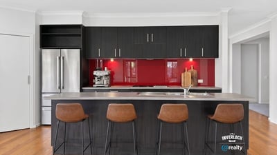 Modern kitchen featuring sleek cabinetry, a striking red backsplash, and spacious island with bar seating.