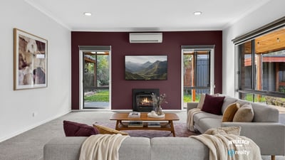Cozy living room with modern features, featuring a fireplace and large windows overlooking a private outdoor space.
