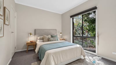 Bright bedroom featuring large windows, cozy furnishings, and a peaceful view of the outdoor greenery.