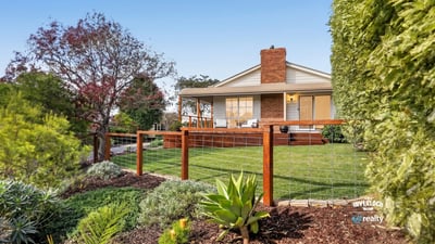 This inviting home features a spacious yard surrounded by vibrant landscaping and a welcoming front porch.