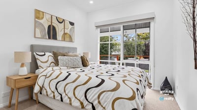 Bright bedroom featuring large windows, modern decor, and a cozy layout, ideal for relaxation and rest.