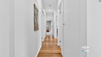 Bright and inviting hallway featuring warm wooden floors and a modern, open layout.