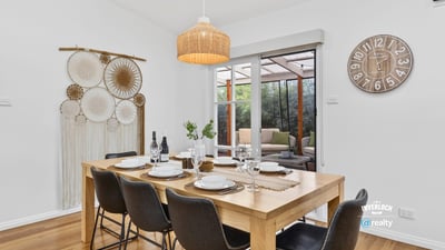 Bright dining area features a spacious table, inviting decor, and views of a cozy outdoor space.