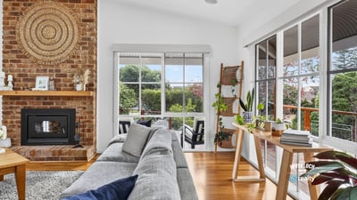 Bright, inviting living space featuring a cozy fireplace and panoramic views of the surrounding gardens.