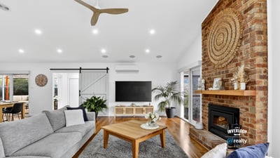 Bright and inviting living space featuring a striking brick fireplace and modern ceiling fan, perfect for gatherings.