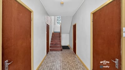 Spacious hallway with wooden doors, leading to a staircase and inviting natural light throughout the space.