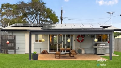 This modern home features a spacious outdoor area with solar panels and a built-in grill for entertaining.