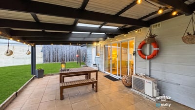 Spacious outdoor patio with hanging lights and lawn, perfect for gatherings and relaxed evenings.