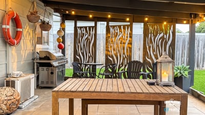 Discover an inviting outdoor space featuring a cozy dining area, grill, and decorative privacy screens.