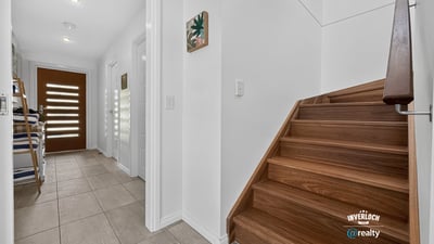 Modern entryway featuring open space, inviting natural light, and a warm wooden staircase.
