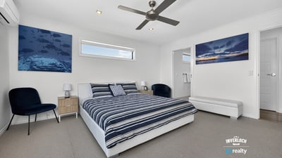 Light-filled bedroom featuring modern decor, ample space, and beautiful ocean-themed artwork for a refreshing atmosphere.