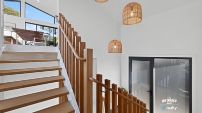 Bright and airy entryway featuring modern lighting and open staircase, seamlessly connecting indoor and outdoor spaces.