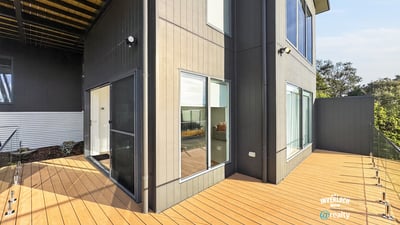 Modern home featuring a spacious outdoor deck and large windows, perfect for entertaining and natural light.