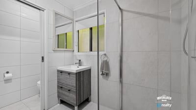 Modern bathroom featuring dual mirrors, a spacious shower, and sleek cabinetry for efficient storage.
