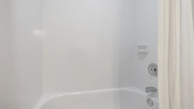 Bright and clean bathtub area featuring a modern showerhead and convenient wall-mounted essentials.