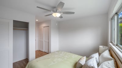 Bright and airy bedroom featuring a ceiling fan, ample closet space, and large windows for natural light.