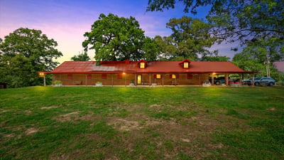 Discover this spacious home set on a sprawling green lot, featuring a distinctive red roof and open outdoor space.