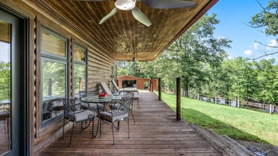 Spacious covered porch with ample seating, perfect for enjoying panoramic views of the surrounding landscape.