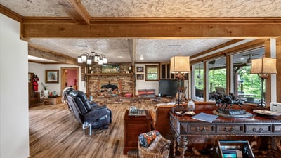 Spacious living area with a rustic fireplace, natural light, and inviting views of the outdoors.