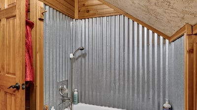 Cozy bathroom featuring a unique corrugated metal accent wall and a comfortable tub for relaxation.