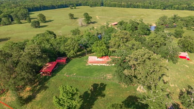 Expansive rural property featuring large open fields, mature trees, and a tranquil pond for outdoor enjoyment.