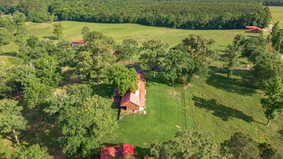 Spacious property featuring a cozy home surrounded by lush greenery and expansive fields, perfect for outdoor enthusiasts.