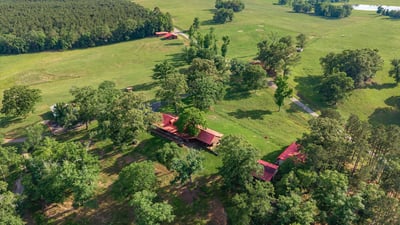 Sprawling ranch property with expansive greenery, scenic views, and multiple outbuildings nestled in nature.