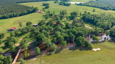 Expansive countryside property featuring lush greenery, flowing water, and ample space for outdoor activities and development.