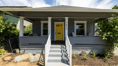 This inviting home features a vibrant yellow door, spacious front porch, and landscaped yard for outdoor enjoyment.